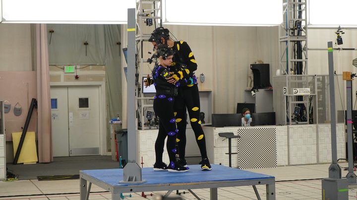 Ariel Winter and Evan Evagora hug while wearing performance-capture suits in a scene from filming of The Quarry game.