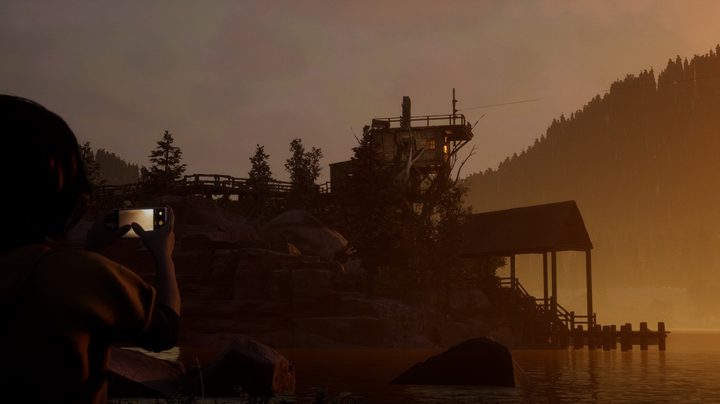 A character takes a photo of the lake and mountain in a scene from The Quarry game.