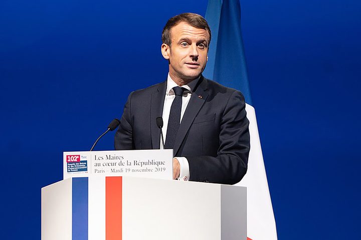 French President Emmanuel Macron stands at a podium.