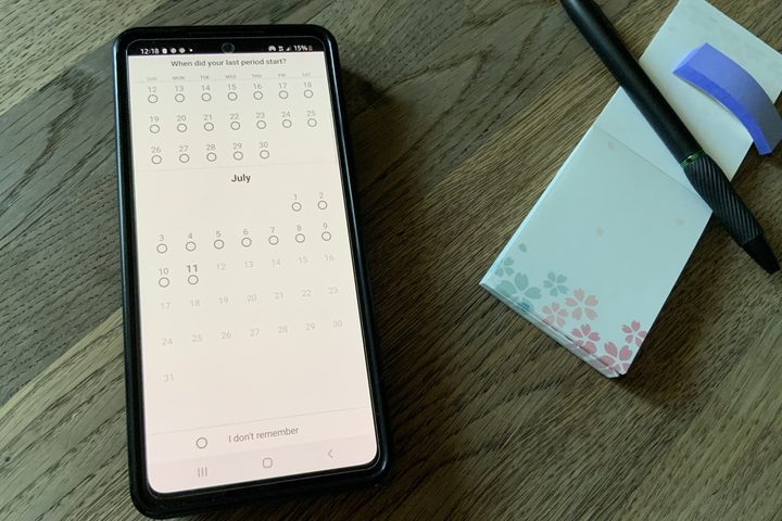Flo chart screen visible on phone with notepad and pen nearby.