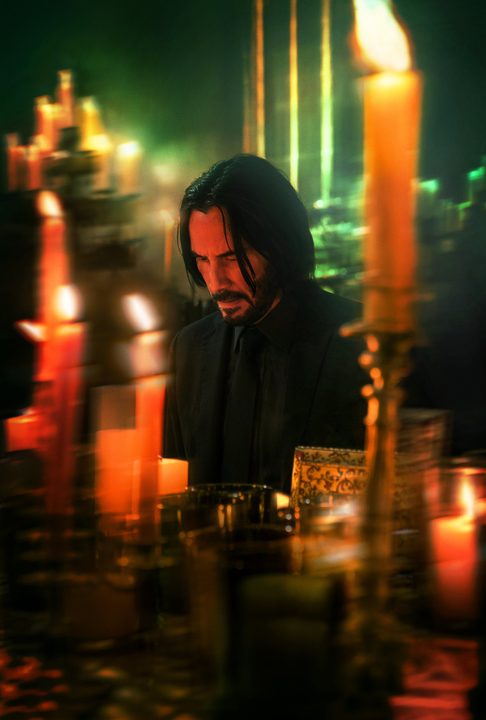 Keanu Reeves kneeling at a candlelit altar in John Wick: Chapter 4.