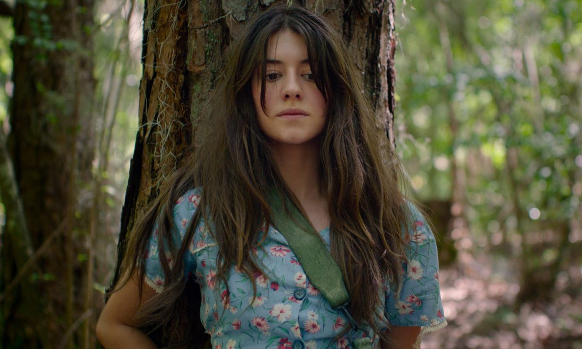 Kya Clark sits against a tree in Where the Crawdads Sing.