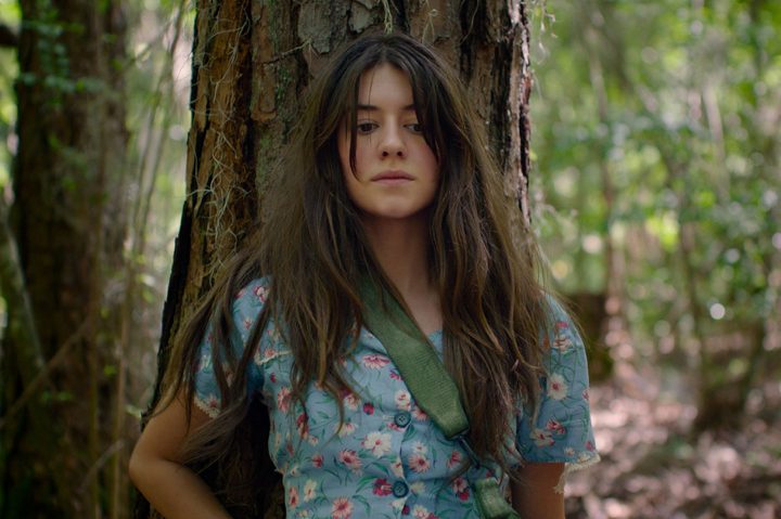 Kya Clark sits against a tree in Where the Crawdads Sing.