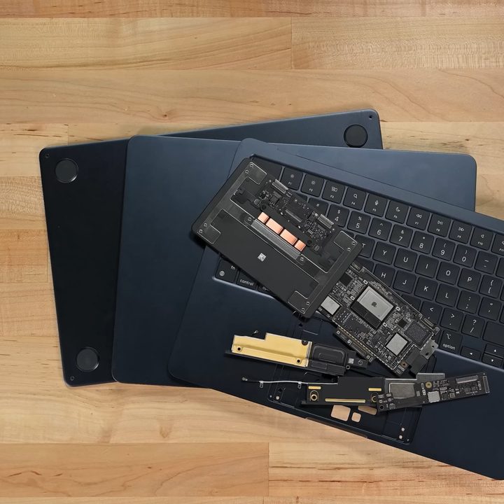 The torn-down M2 MacBook Air rests on a wooden floor.
