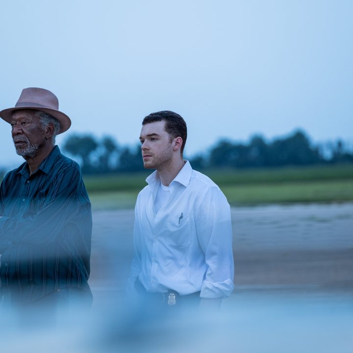 Morgan Freeman and Cameron Monaghan stand next to each other and stare into the distance in a scene from Paradise Highway.
