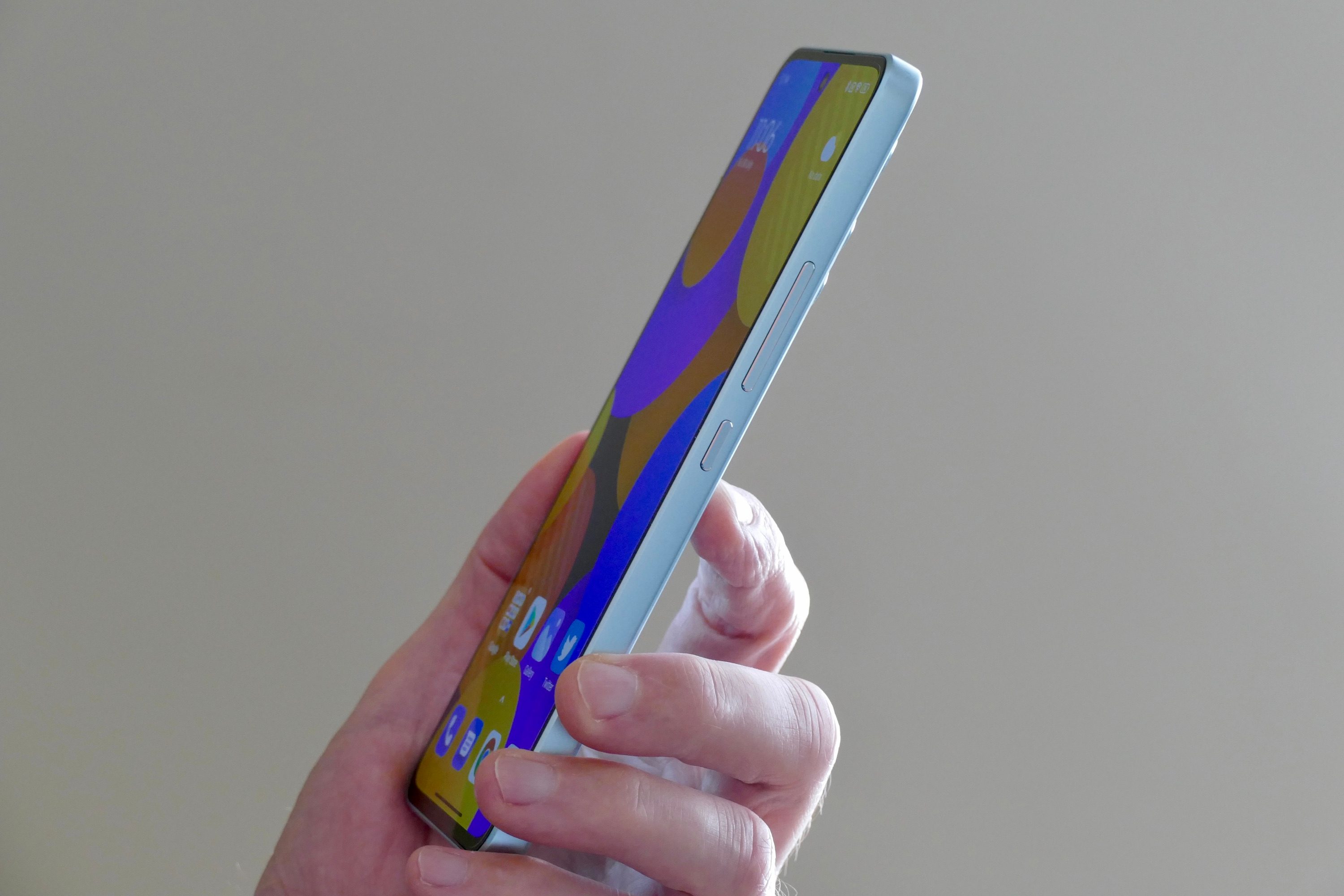 The side of the Xiaomi 12 Lite, held in a mans hand.