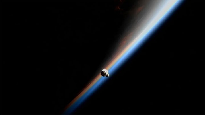 The SpaceX Dragon resupply ship approaches the space station during an orbital sunrise above the Pacific Ocean.