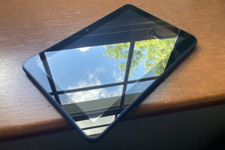 2022 Amazon Fire 7 sitting on a windowsill with a clear skyed day reflecting off the display.