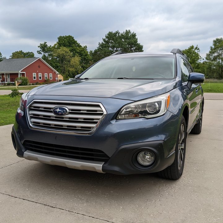 A photo of a blue Subaru Outback in a parking lot.