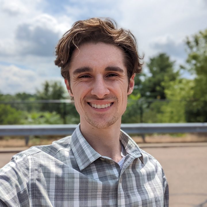A selfie of Joe Maring. He's standing outside, smiling, and wearing a green button-down shirt.