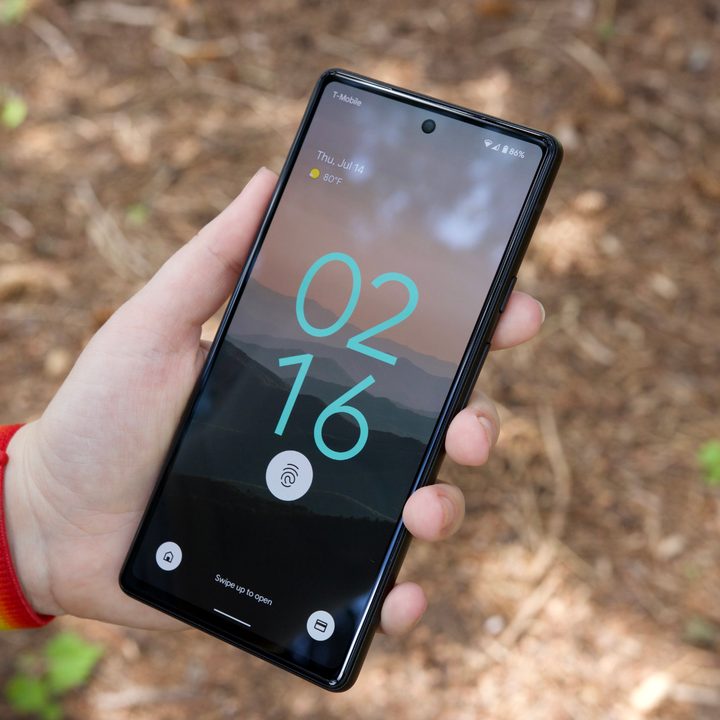 Someone holding the Google Pixel 6a. The display is on and showing the lock screen.