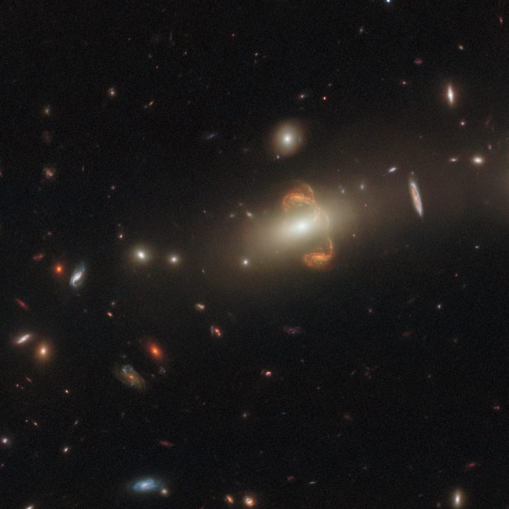 Gravitational lensing has resulted in a mirror image of the galaxy near the center of this image, creating a captivating centerpiece. A third distorted image of the galaxy appears as a bridge between them.