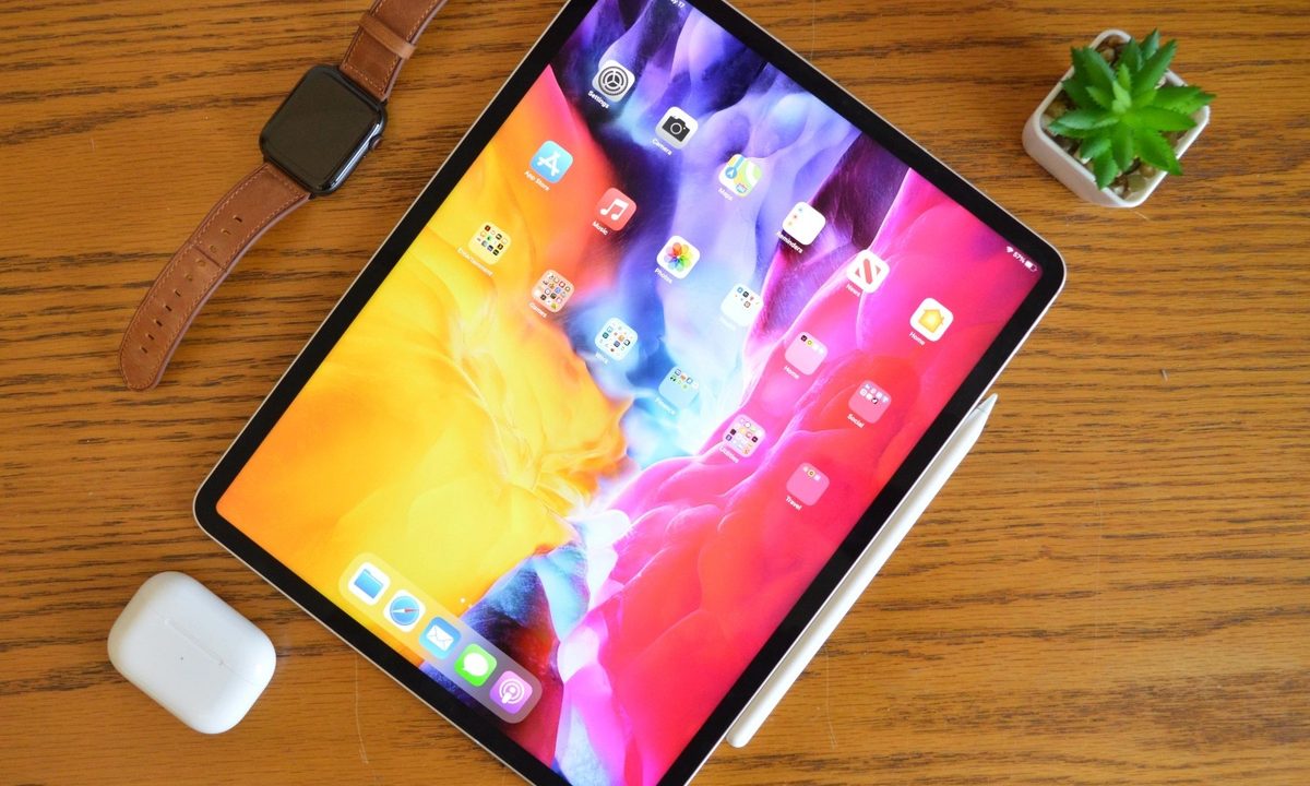 The iPad Pro on a desk next to a stylus and AirPods.