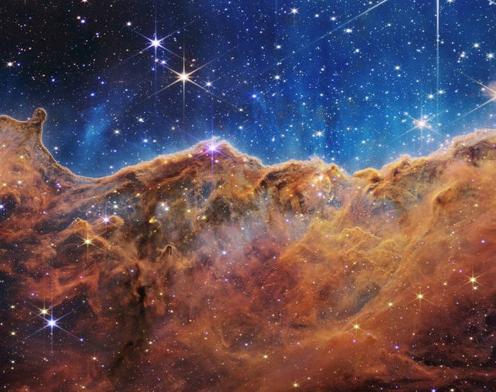 This landscape of “mountains” and “valleys” speckled with glittering stars is actually the edge of a nearby, young, star-forming region called NGC 3324 in the Carina Nebula.