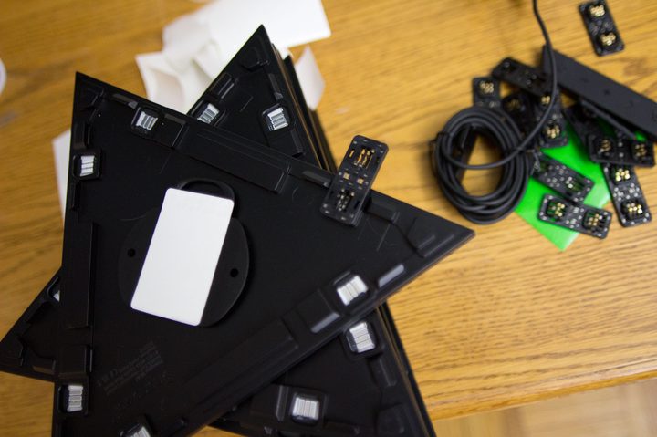 The underside of a Nanoleaf Shapes light tile with the mounting plate and adhesive pad showing.