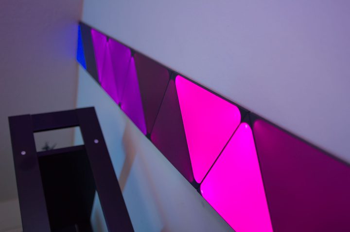 Nanoleaf Shapes tiles mounted on wall, shining a pattern of red colors.