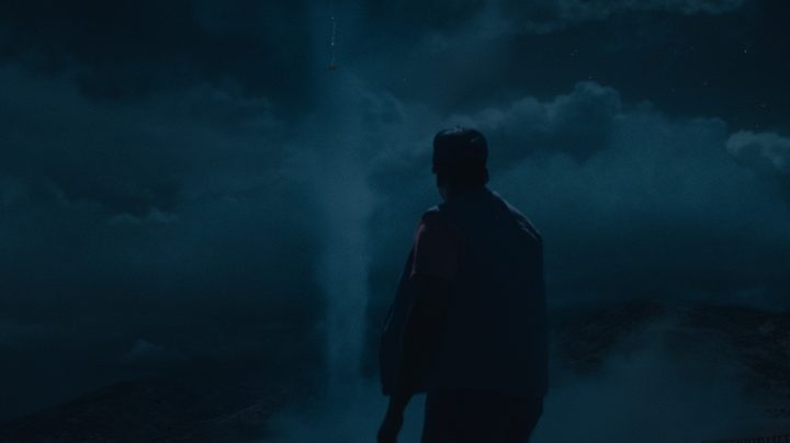 Daniel Kaluuya looks up at a funnel cloud in the night sky in a scene from Nope.
