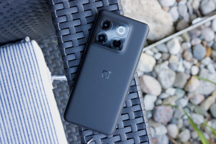 The OnePlus 10T laying face-down on the arm of an outdoor chair.