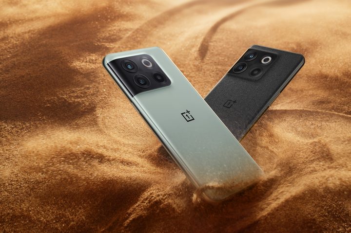 The OnePlus 10T in green and black. They're both sitting on top of sand.