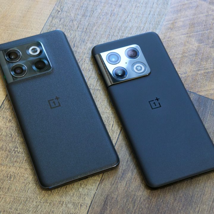 The OnePlus 10T and OnePlus 10 Pro lying a wood desk next to each other.