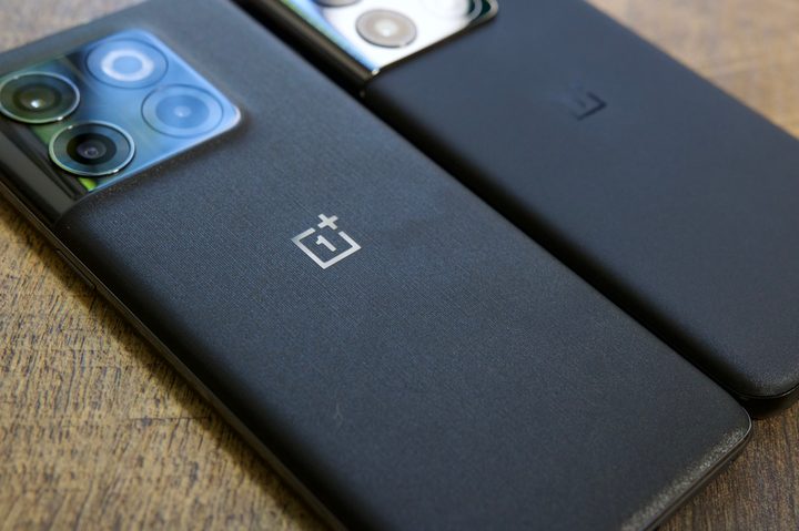 The OnePlus 10T and OnePlus 10 Pro lying a wood desk next to each other.
