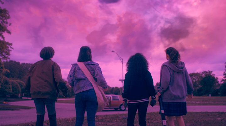 Sofia Rosinsky, Riley Lai Nelet, Camryn Jones, and Fina Strazza look up at a pink sky in a scene from Paper Girls.