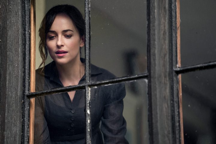 Dakota Johnson as Anne Elliot looking out a window in Persuasion.