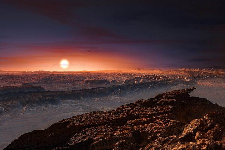 This artist’s impression shows a view of the surface of the planet Proxima b orbiting the red dwarf star Proxima Centauri, the closest star to the Solar System. The double star Alpha Centauri AB also appears in the image. Proxima b is a little more massive than the Earth and orbits in the habitable zone around Proxima Centauri, where the temperature is suitable for liquid water to exist on its surface.