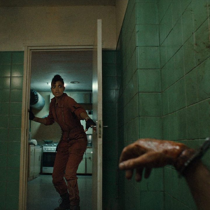 Ella Balinska looks in a door and sees a bloody, handcuffed hand in a scene from Netflix series Resident Evil.