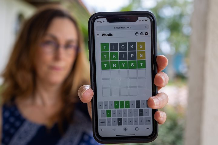 Woman holding an iPhone with Wordle.