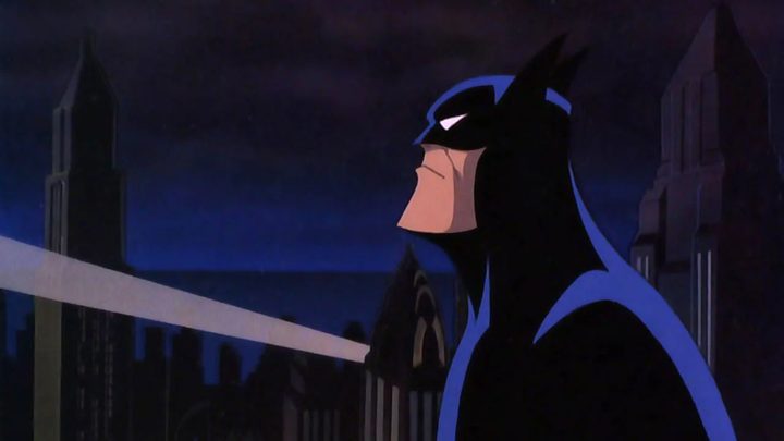 Batman looking up at the Bat-signal in Gotham City.