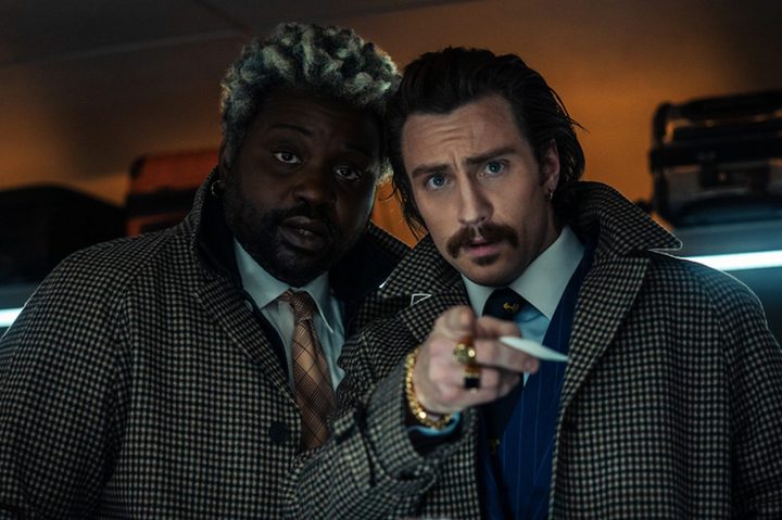 Brian Tyree Henry and Aaron Taylor Johnson stare and point in a scene from Bullet Train.