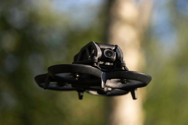 The DJI Avata flying in a forest.