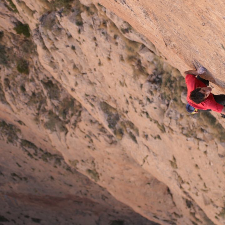Alex Honnold climbing a wall in a scene from Edge of the Unknown.