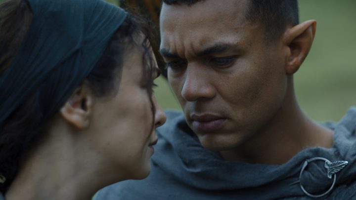 Ismael Cruz Cordova as Arondir stares into the eyes of a human woman in a scene from The Lord of the Rings: The Rings of Power.