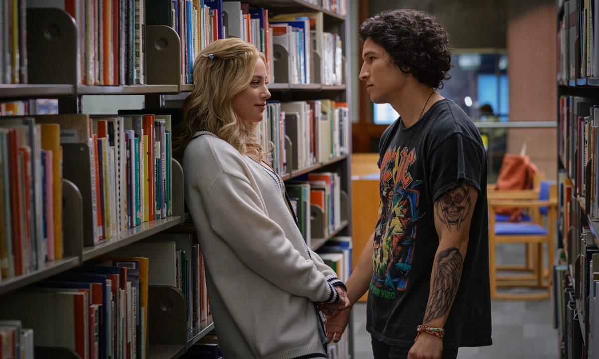 Lili Reinhart and Danny Ramirez stand in between two bookshelves in Look Both Ways.