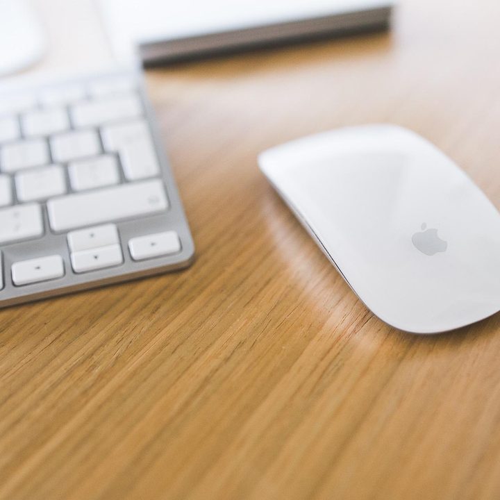 Magic Mouse next to a Mac keyboard on a desk.