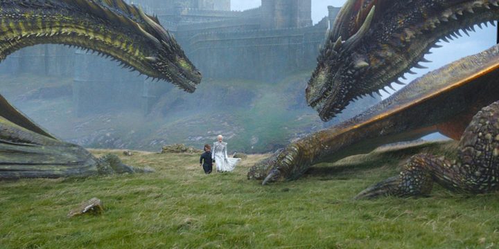 Tyrion waking alongside Daenerys with Rhaegal and Drogon looming overhead.