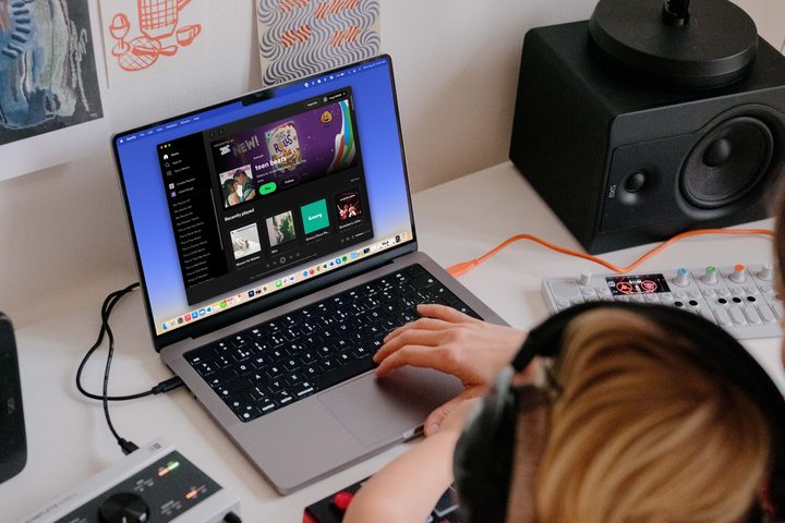 People with headphones listening to Spotify on a MacBook.