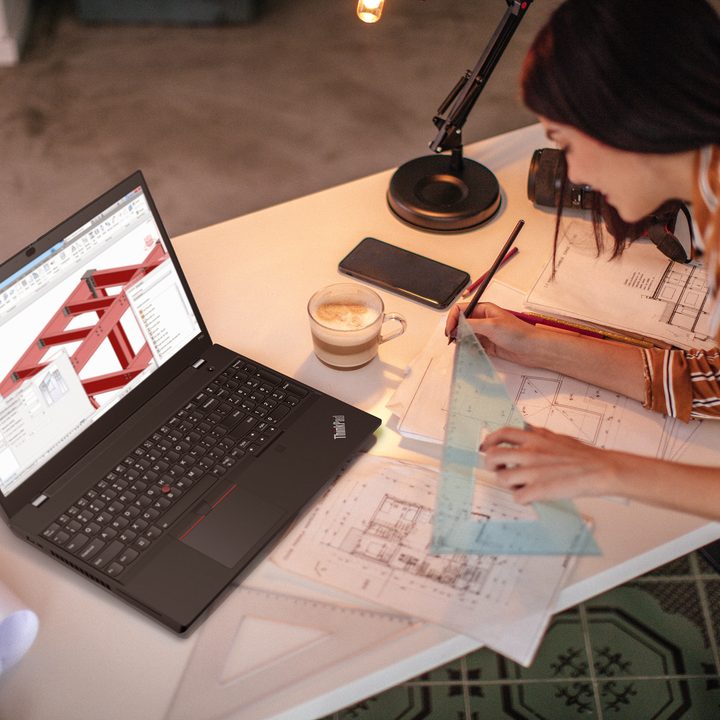 A designer sits by a desk as she works on a project with the Lenovo ThinkPad 15v next to her.