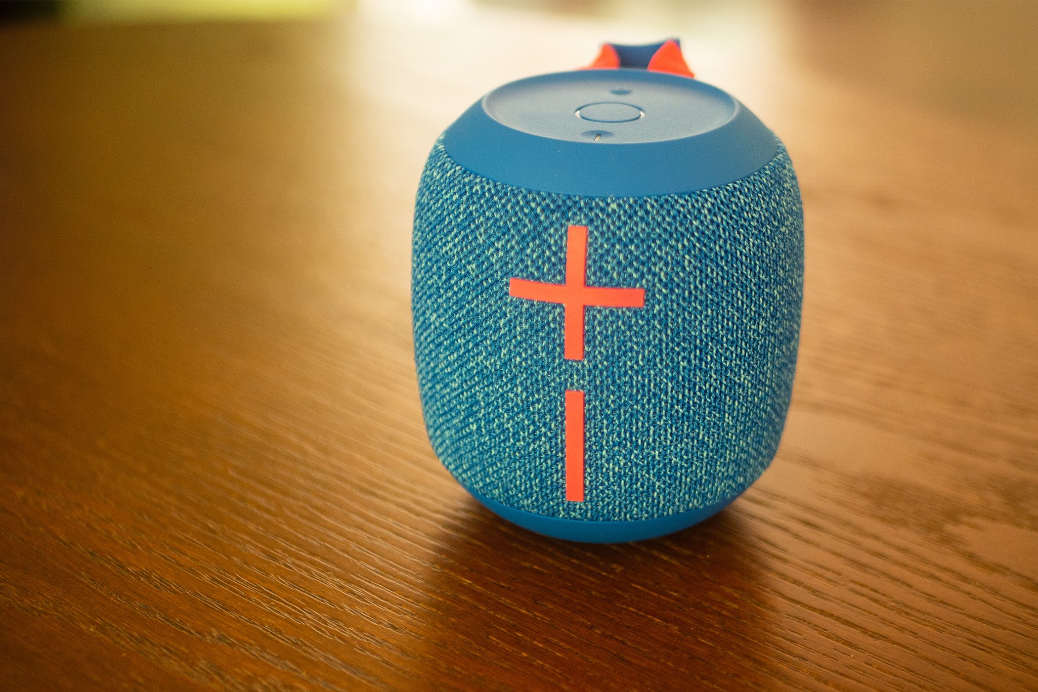 A Wonderboom 3 speaker is sitting on a wood-tone table.