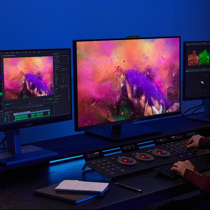 A woman sits by a desk as she works using an Asus ProArt Display OLED PA32DC.