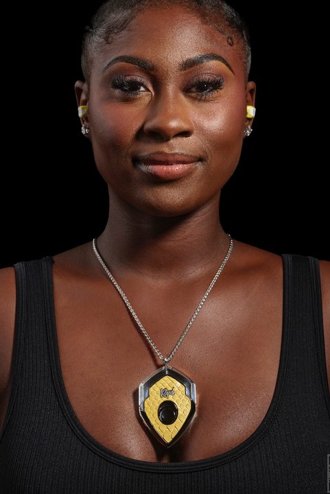 Woman wearing Close-up of Klipsch/Ear Micro T10 Bespoke Ear Computer with charging case pendant.