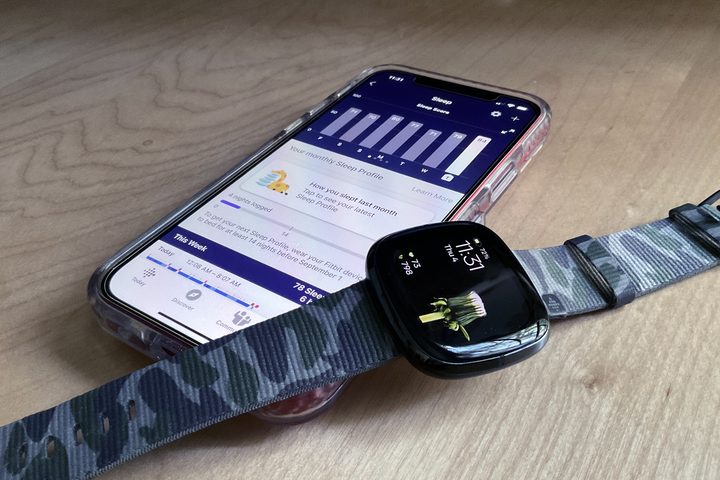 An iPhone 12 with Sleep Profiles data displayed on its screen with a Fitbit Sense resting on top of it.