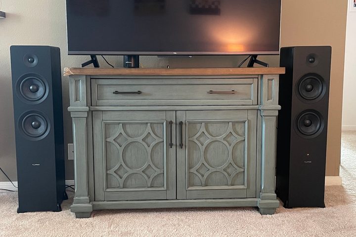 The Fluance Ai81 speakers set up on each side of a TV stand.