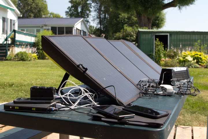 Goal Zero Nomad 100 solar panels on picnic table, charging devices.