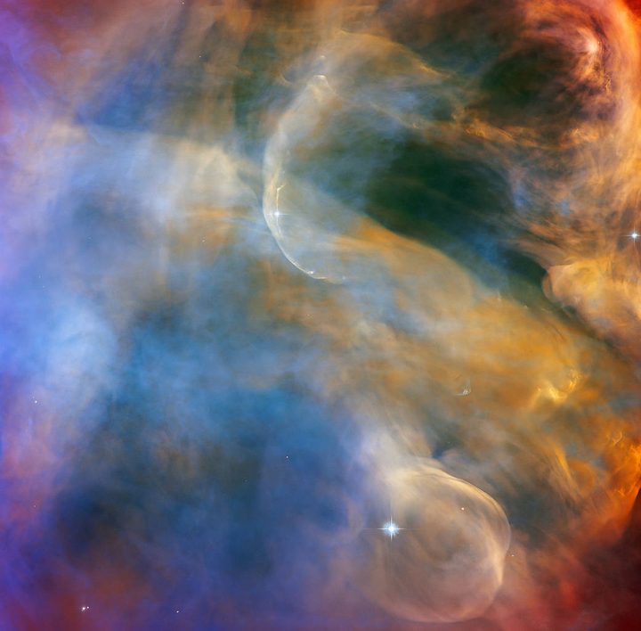 This celestial cloudscape from the NASA/ESA Hubble Space Telescope captures the colorful region in the Orion Nebula surrounding the Herbig-Haro object HH 505. Herbig-Haro objects are luminous regions surrounding newborn stars that form when stellar winds or jets of gas spew from these infant stars creating shockwaves that collide with nearby gas and dust at high speeds. In the case of HH 505, these outflows originate from the star IX Ori, which lies on the outskirts of the Orion Nebula around 1,000 light-years from Earth. The outflows themselves are visible as gracefully curving structures at the top and bottom of this image. Their interaction with the large-scale flow of gas and dust from the core of the nebula distorts them into sinuous curves.