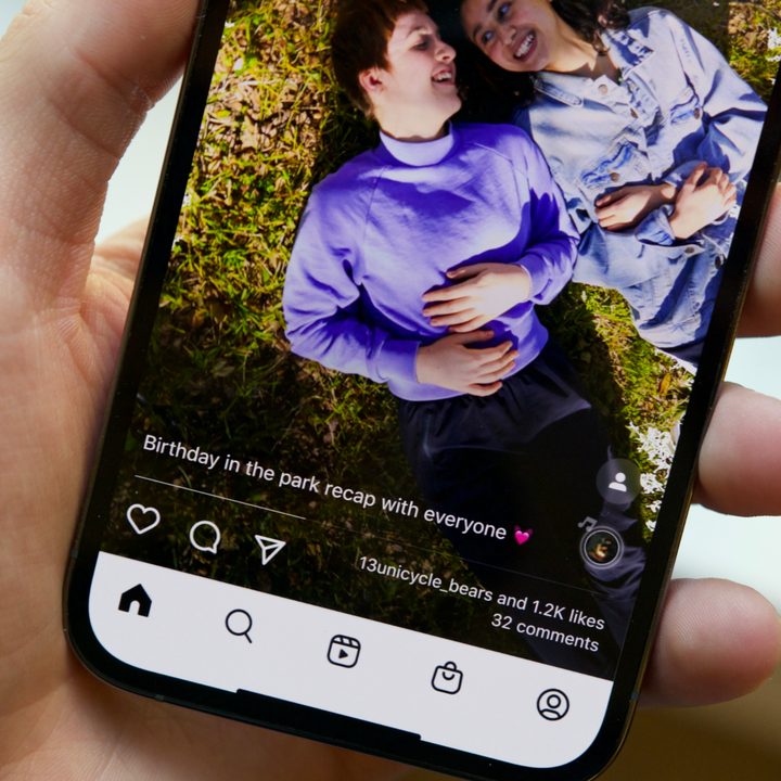 Someone holding an iPhone. The screen shows a full-screen Instagram post.