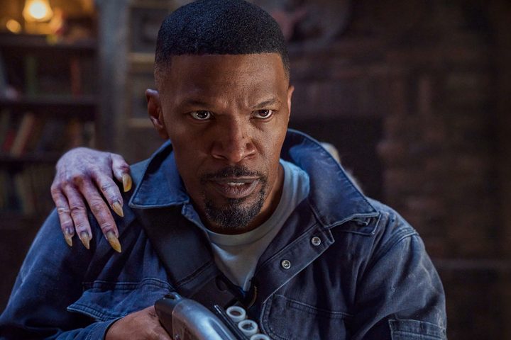 Jamie Foxx stands with a shotgun while a vampire's hand goes over his shoulder.