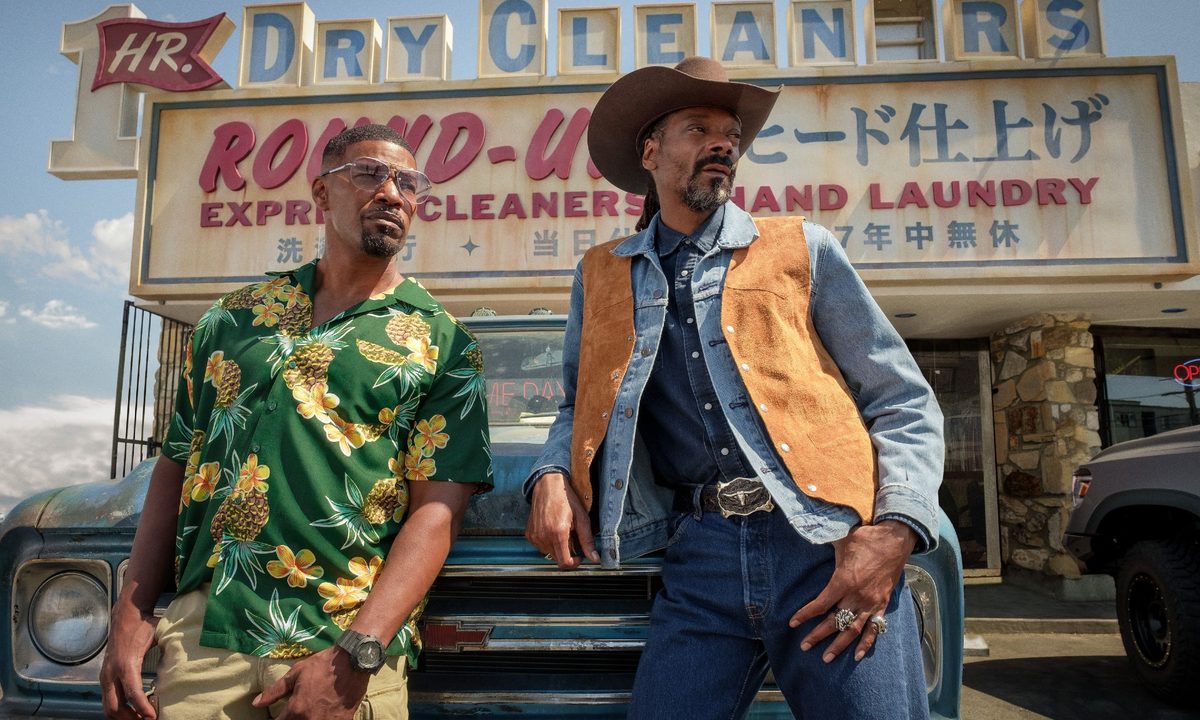Jamie Foxx and Snoop Dogg lean against a truck in a scene from Day Shift.